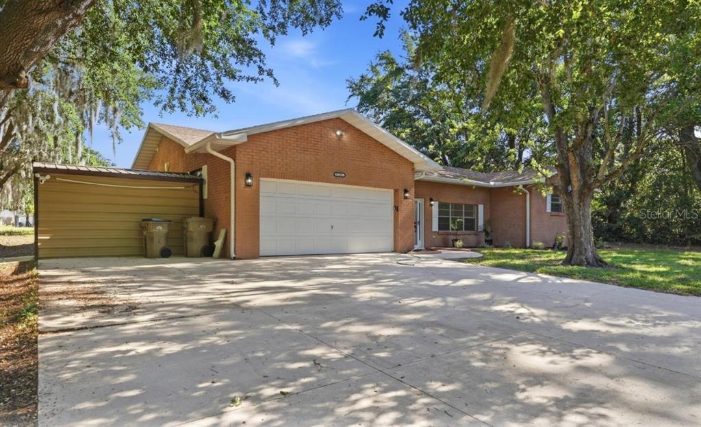 A single-story brick house with a two-car garage and a concrete driveway — 33201 COVENTRY DRIVE, LEESBURG, FL