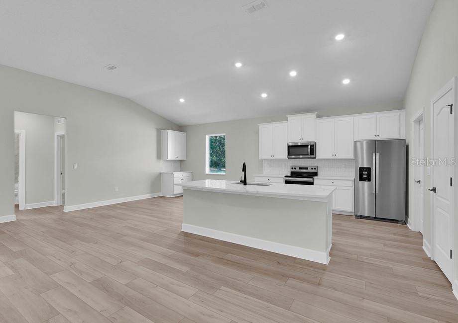 A modern kitchen with white cabinets, stainless steel appliances, and a central island with seating — 17399 SW 26TH TERRACE ROAD, OCALA, FL