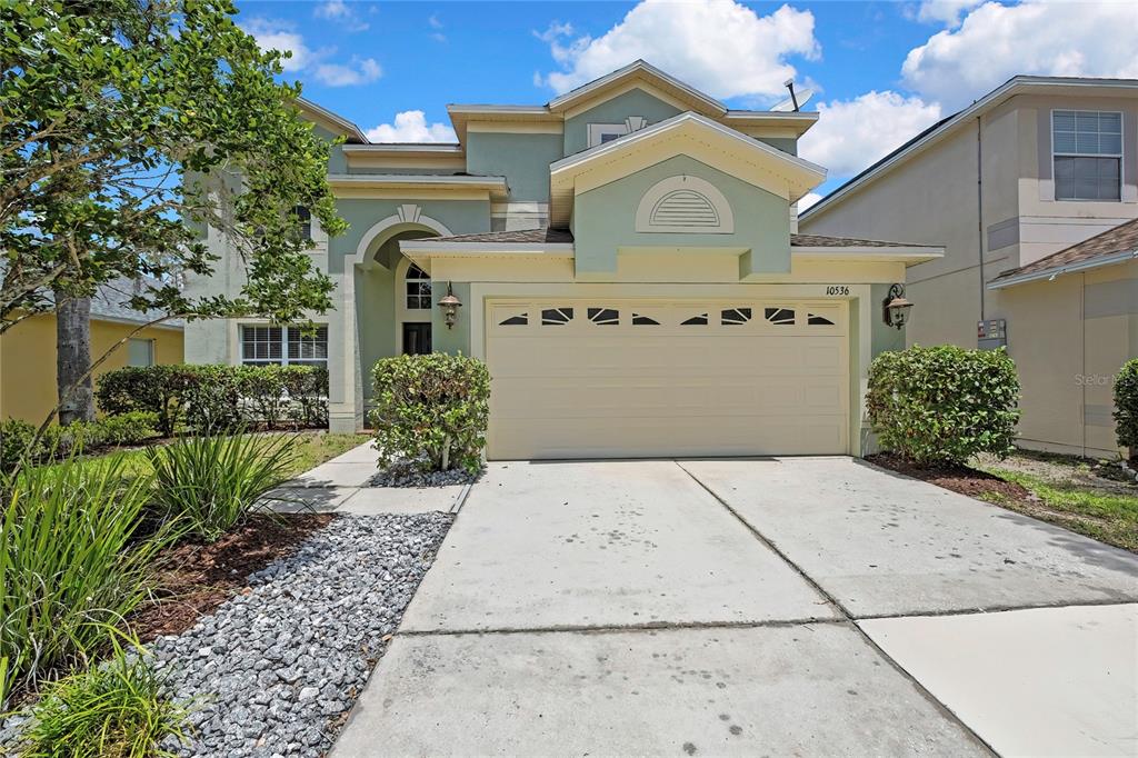A two-story house with a light green exterior, a two-car garage, and a concrete driveway — 10536 CORAL KEY AVENUE, TAMPA, FL