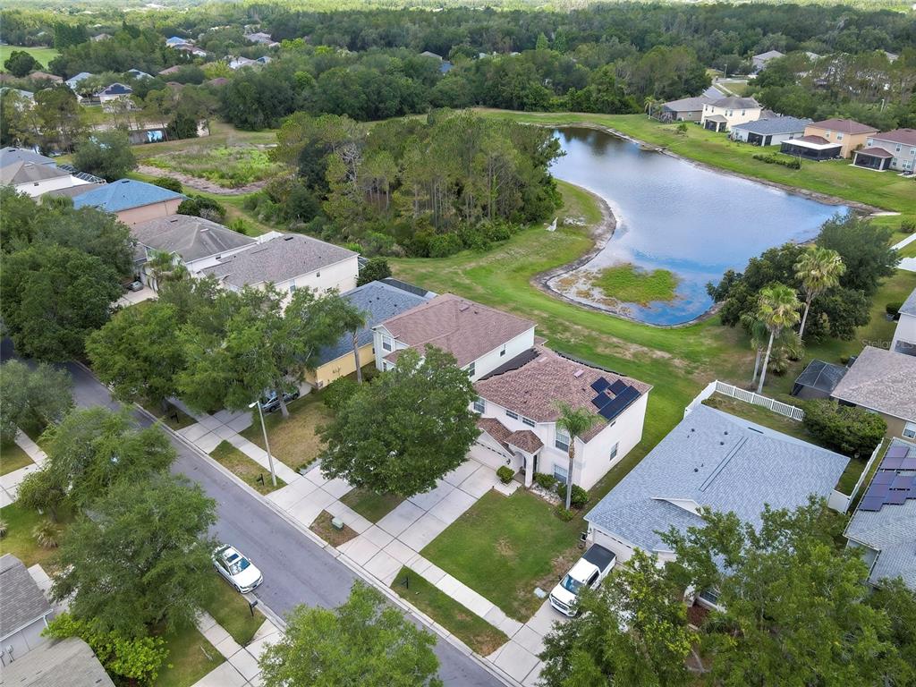 An aerial view shows suburban houses with driveways, trees, and a pond in the background — 10536 CORAL KEY AVENUE, TAMPA, FL
