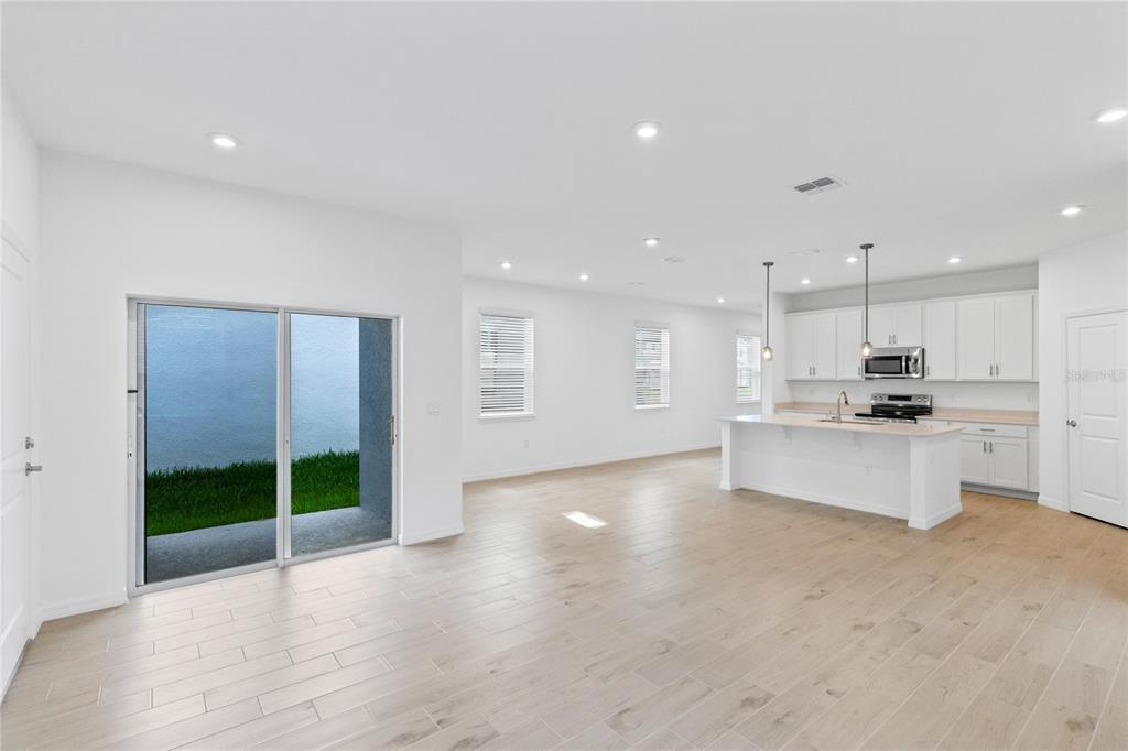 An open-concept kitchen and living area features white cabinets, a central island, and tile flooring — 5746 STOCKADE BOULEVARD, ST CLOUD, FL