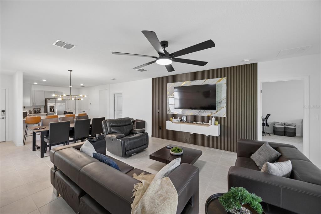 A living room features a dark wood-slatted accent wall with a mounted television and floating console — 5744 LE MARIN WAY, KISSIMMEE, FL