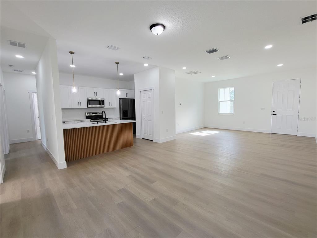 An open-concept kitchen and living area features white cabinetry, a slatted island, and light flooring — 1751 NANDINA COURT NW, PALM BAY, FL