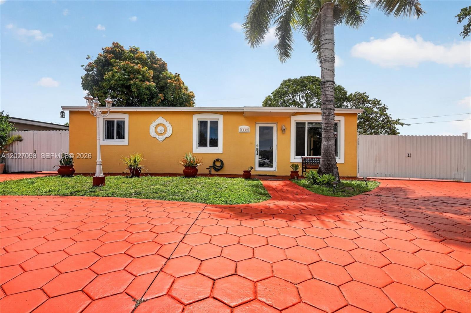 A single-story yellow house features a red hexagonal-patterned driveway and a palm tree — 1440 N 68th Ave, Hollywood FL 33024, HOLLYWOOD, FL