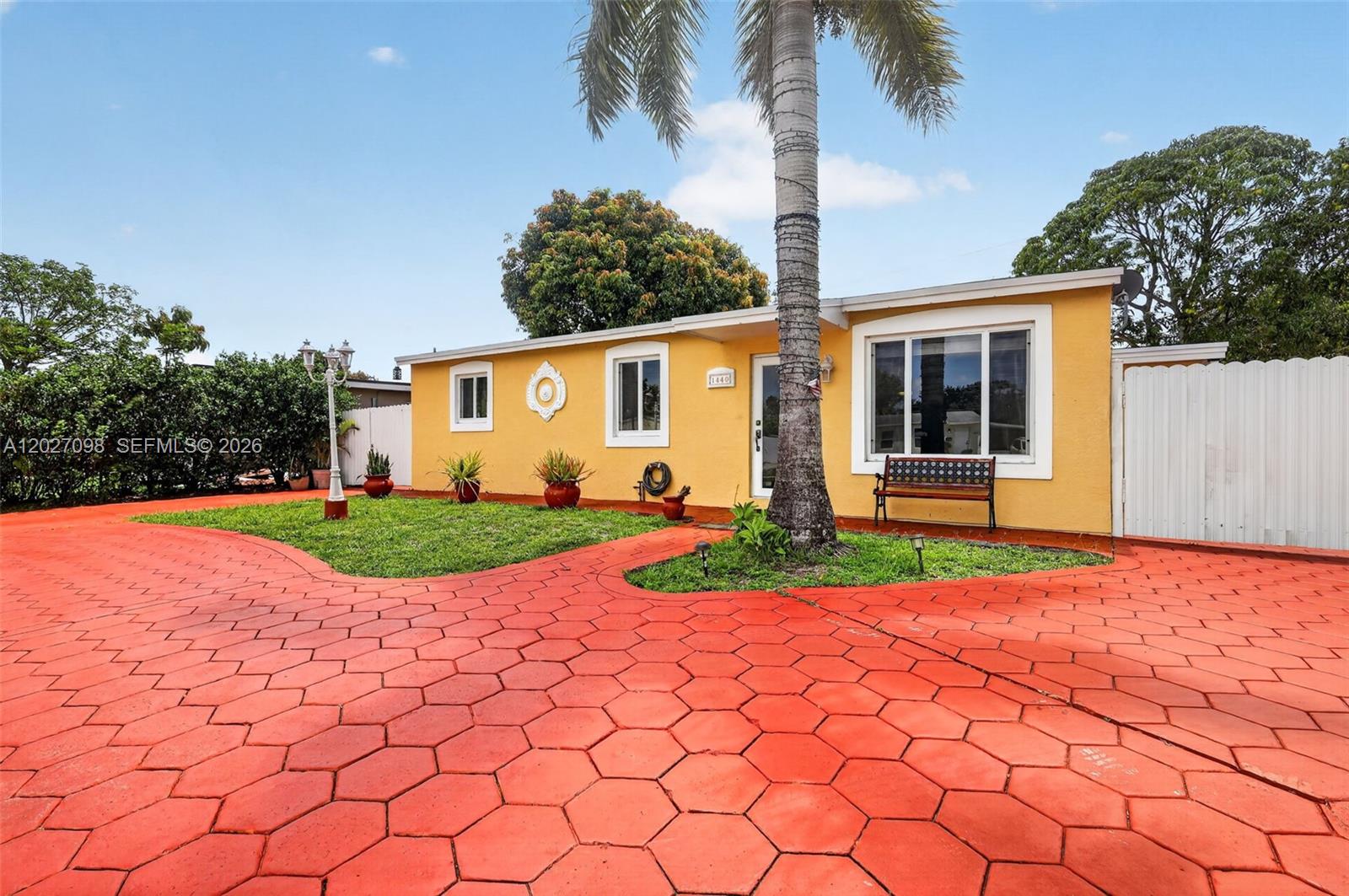 A yellow single-story house features a red hexagonal paver driveway and a palm tree — 1440 N 68th Ave, Hollywood FL 33024, HOLLYWOOD, FL