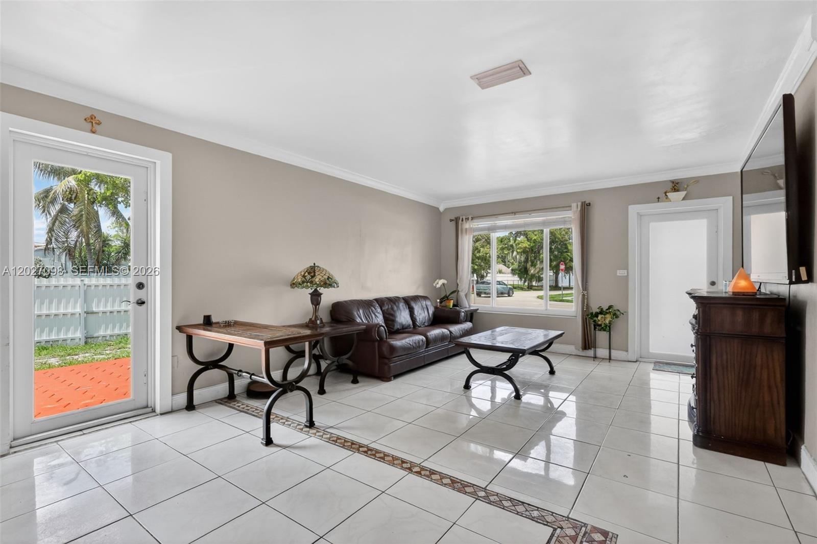 A living room features white tile floors, a brown leather sofa, and two exterior doors — 1440 N 68th Ave, Hollywood FL 33024, HOLLYWOOD, FL