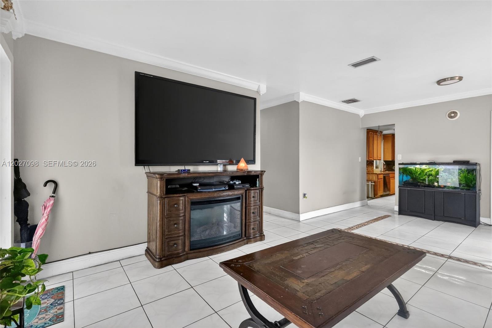 A living room features a large television above a fireplace console, tile flooring, and an aquarium — 1440 N 68th Ave, Hollywood FL 33024, HOLLYWOOD, FL