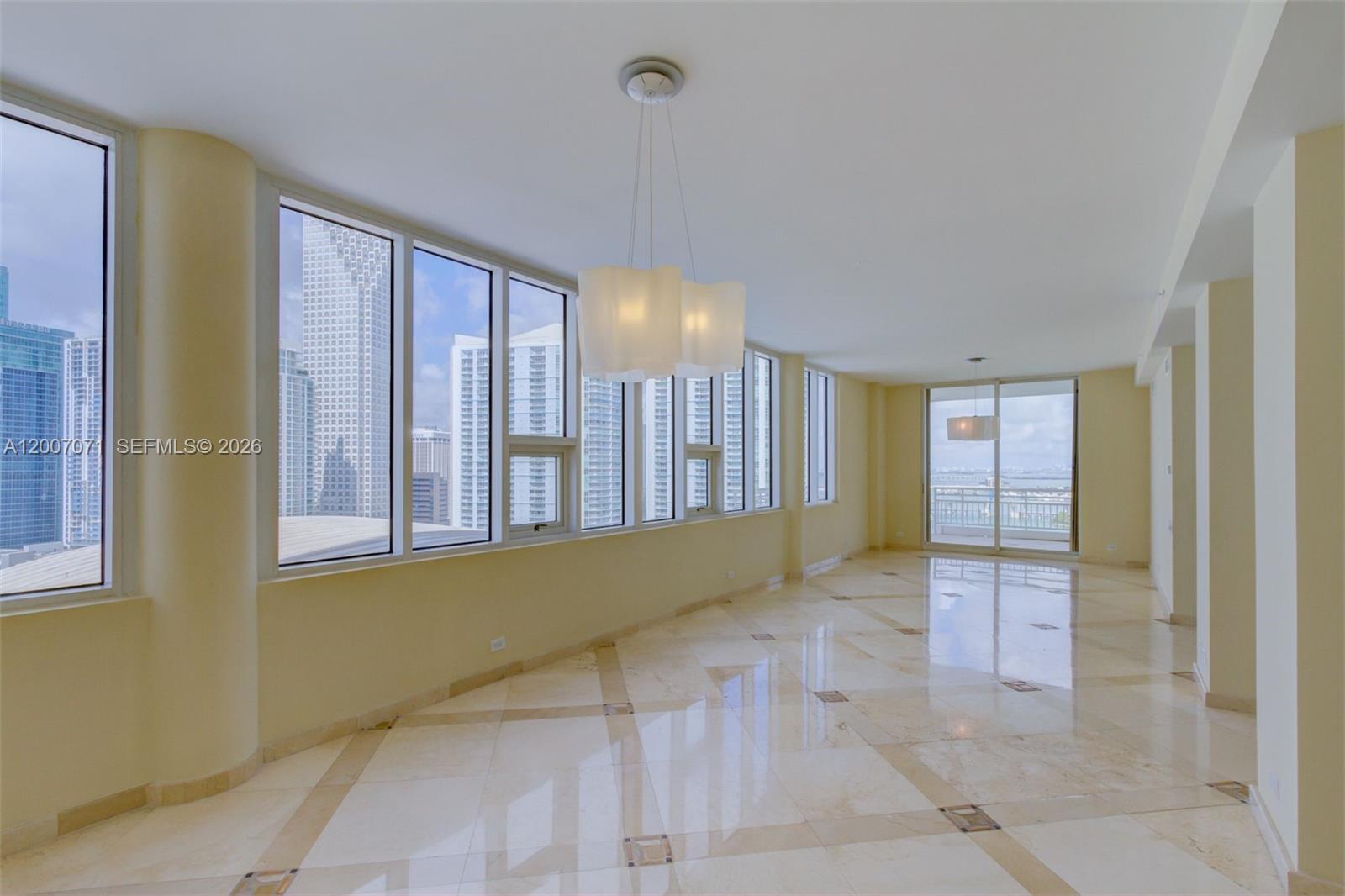 An empty room features polished tile floors, floor-to-ceiling windows, and views of city skyscrapers — 888 Brickell Key Dr # 2802, Miami FL 33131, MIAMI, FL