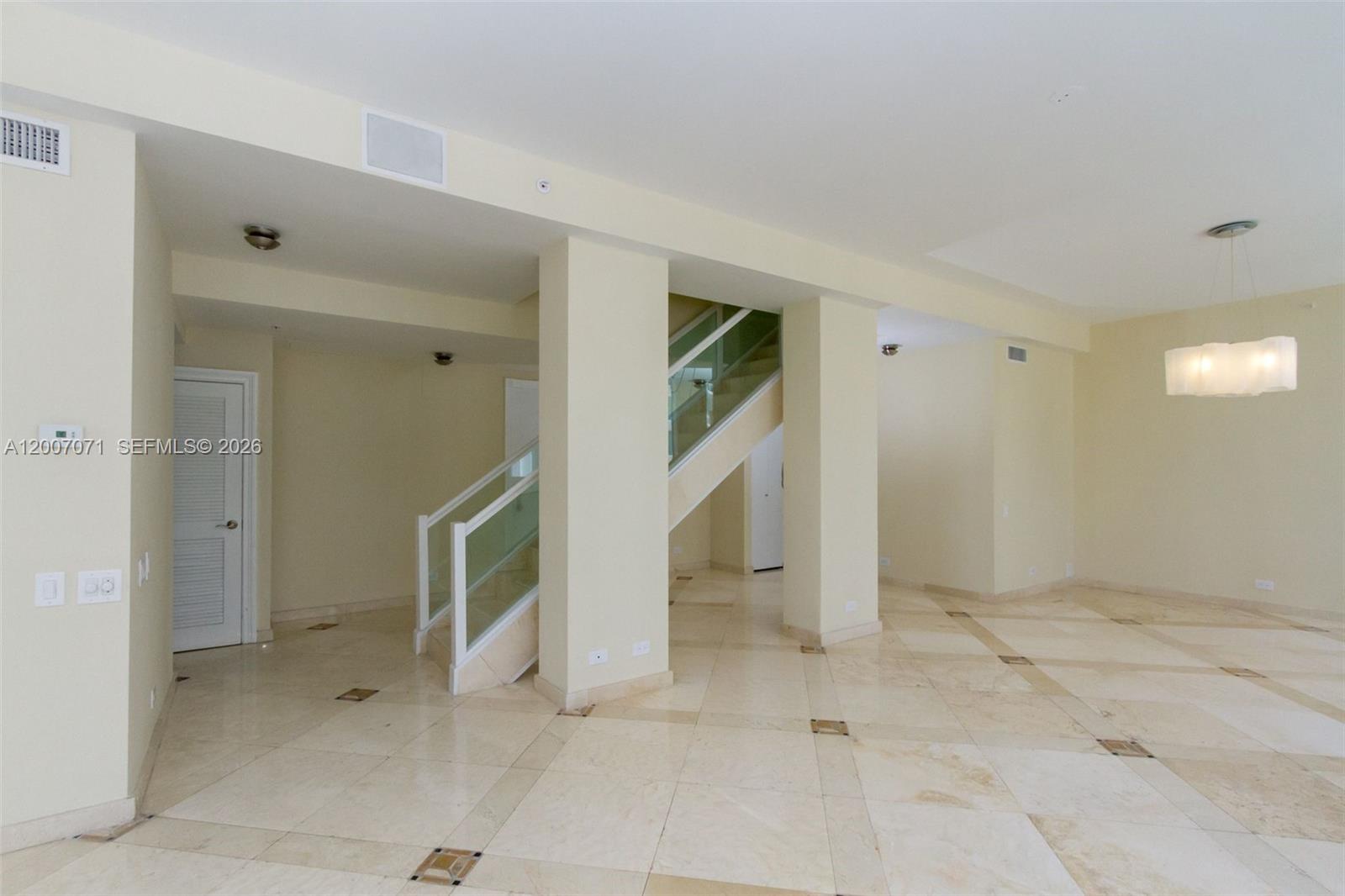 An open living area features light-colored tile floors, a central staircase, and a modern chandelier — 888 Brickell Key Dr # 2802, Miami FL 33131, MIAMI, FL