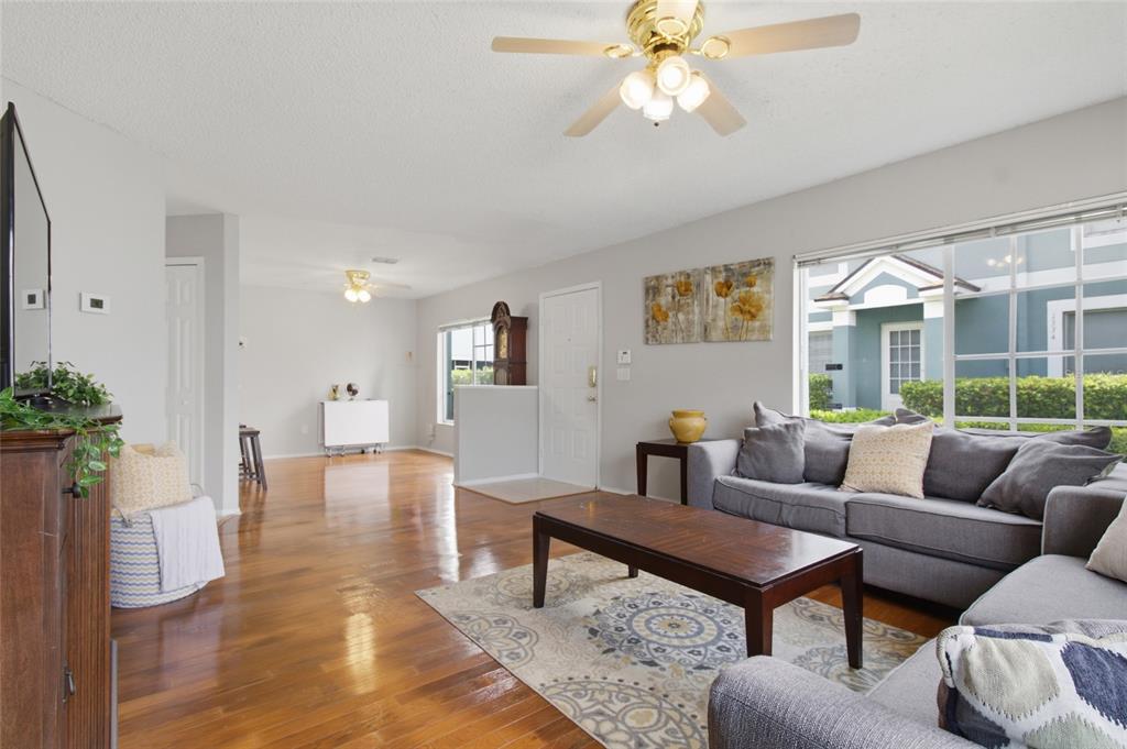 A living room with hardwood floors, a gray sofa, a coffee table, and a ceiling fan — 1328 TWILRIDGE PLACE, BRANDON, FL