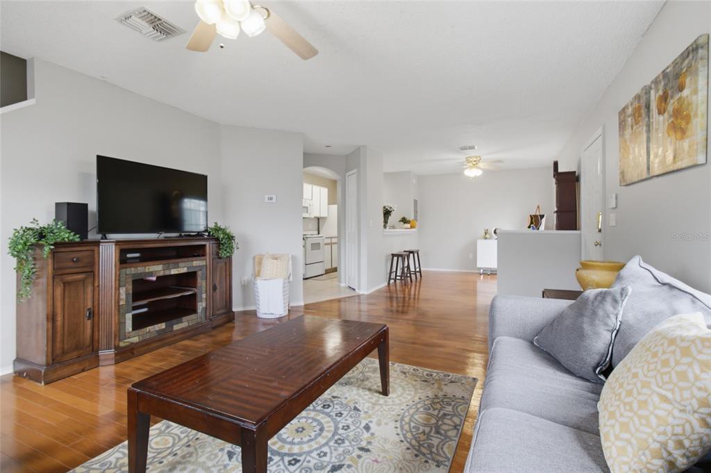 A living room features hardwood floors, a wooden media console, and a gray sofa — 1328 TWILRIDGE PLACE, BRANDON, FL