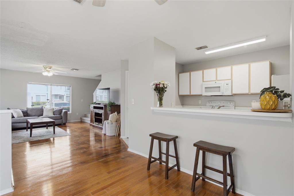 An open-concept living room and kitchen featuring hardwood floors, a breakfast bar, and white cabinetry — 1328 TWILRIDGE PLACE, BRANDON, FL