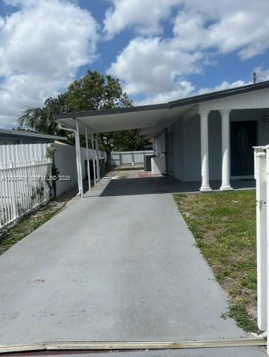 A concrete driveway leads to a covered carport attached to the side of a house — 841 Hialeah Dr, Hialeah FL 33010, HIALEAH, FL