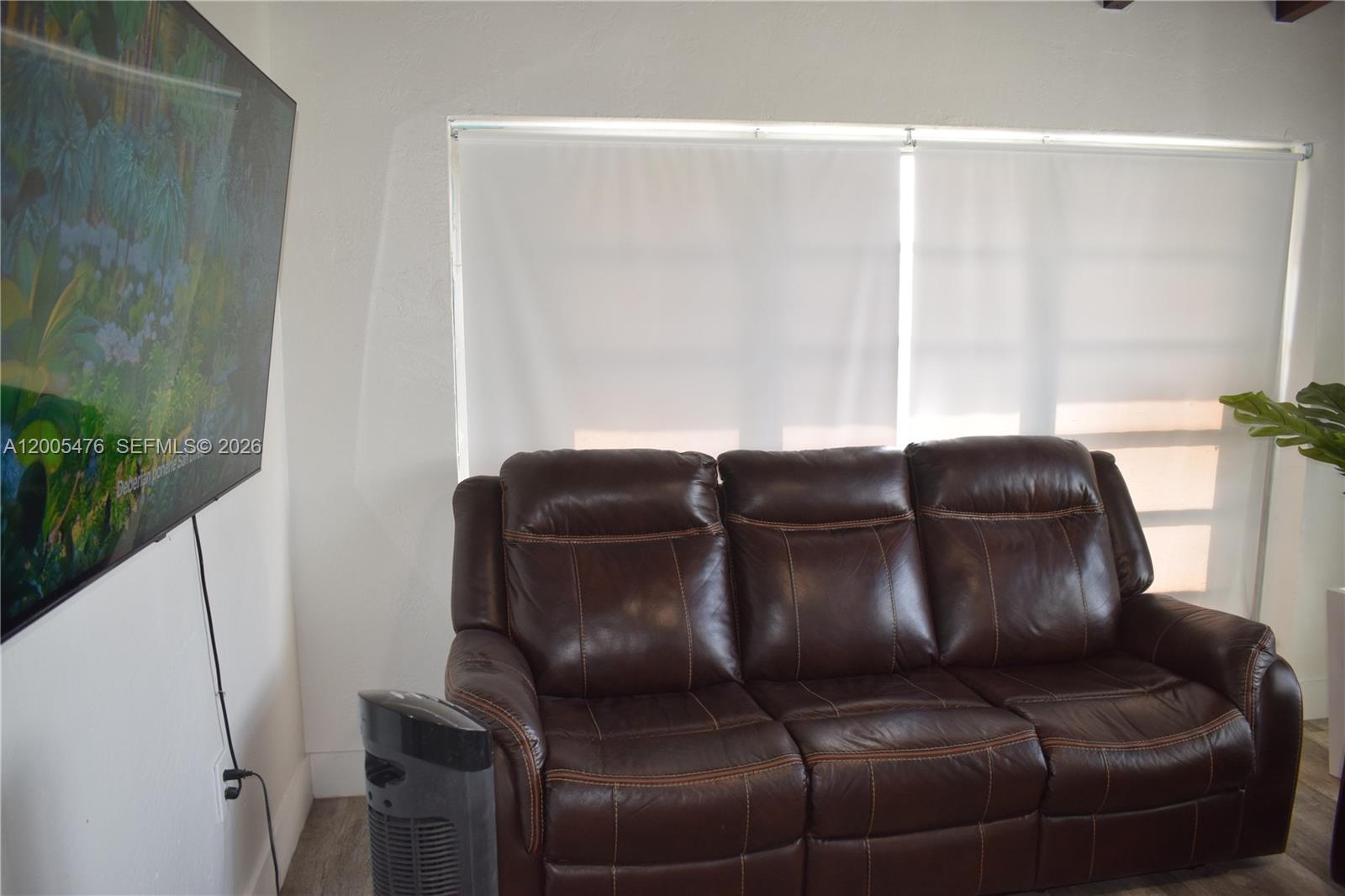A brown leather sofa sits in front of a window with white roller shades — 841 Hialeah Dr, Hialeah FL 33010, HIALEAH, FL