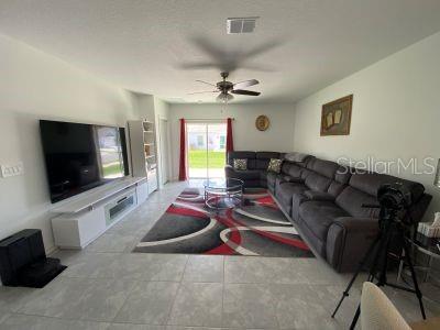 A living room features a large television, a gray sectional sofa, and a patterned rug — 4258 TWISTED TWIG BEND, KISSIMMEE, FL