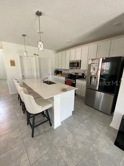 A kitchen with white cabinets, a quartz island, stainless steel appliances, and light tile flooring — 4258 TWISTED TWIG BEND, KISSIMMEE, FL