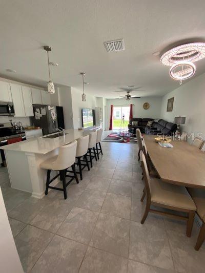 An open-concept kitchen and dining area features a large island, pendant lighting, and tile flooring — 4258 TWISTED TWIG BEND, KISSIMMEE, FL