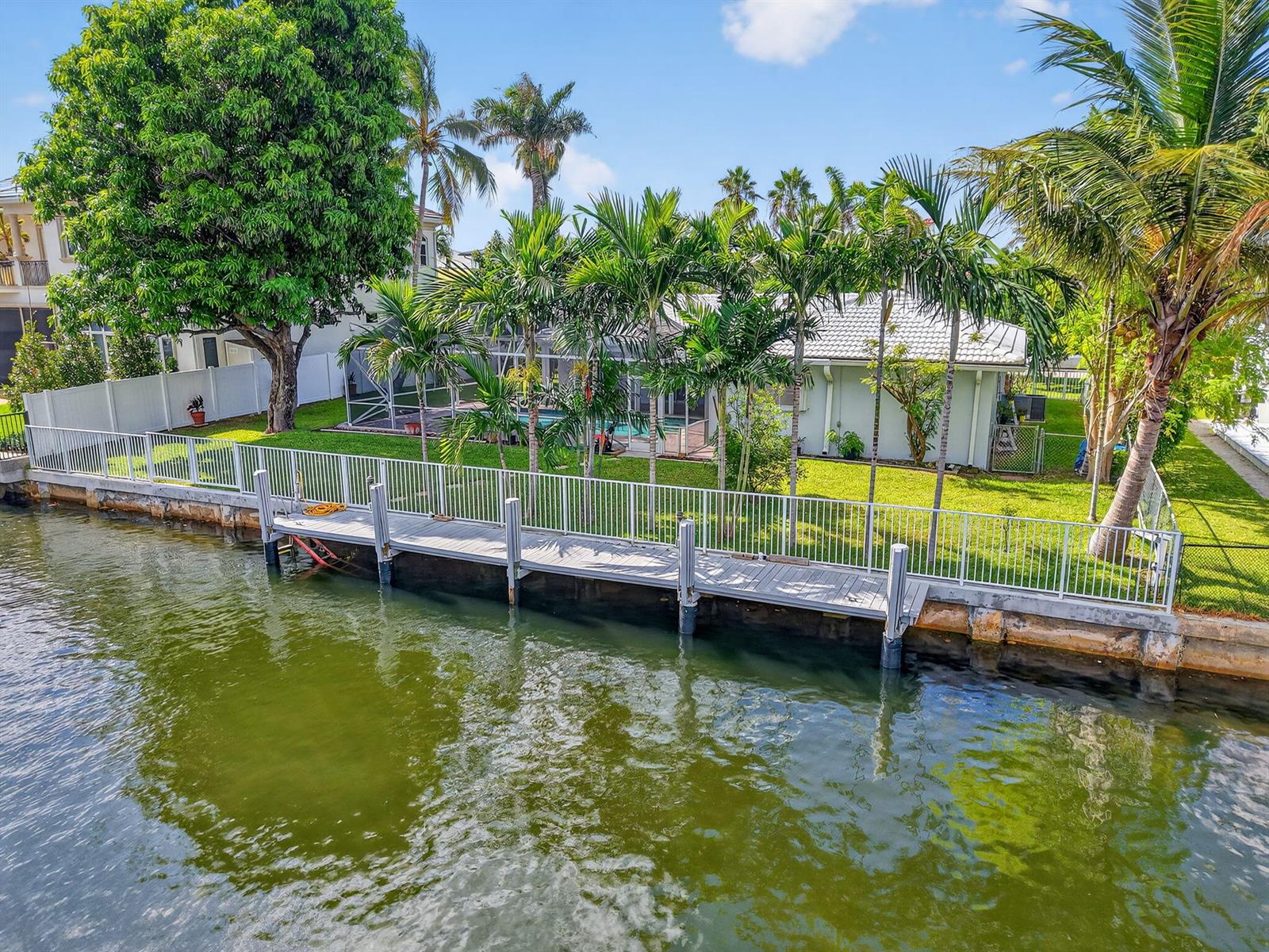 An aerial view of a waterfront house with a backyard, swimming pool, and wooden dock — 937 Banyan Drive, Delray Beach FL 33483, DELRAY BEACH, FL