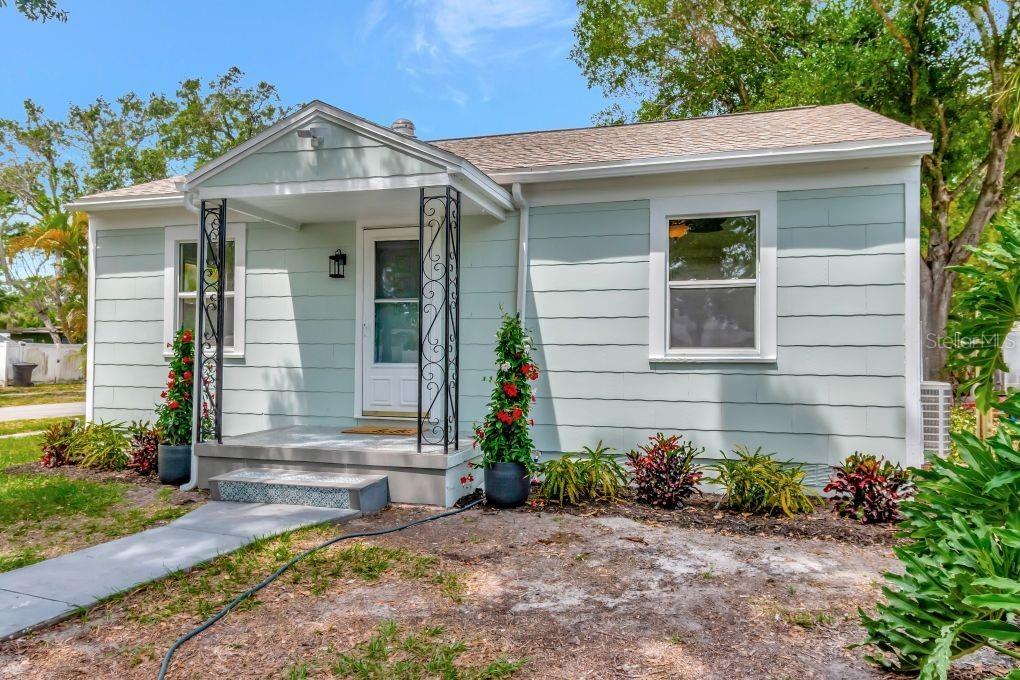 A light green single-story house features a small front porch with decorative metal supports — 1419 55TH STREET S, GULFPORT, FL