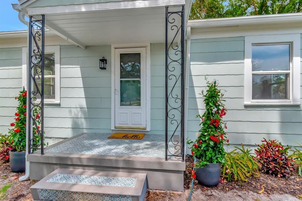 A light green house exterior features a front porch with decorative metal columns and stairs — 1419 55TH STREET S, GULFPORT, FL