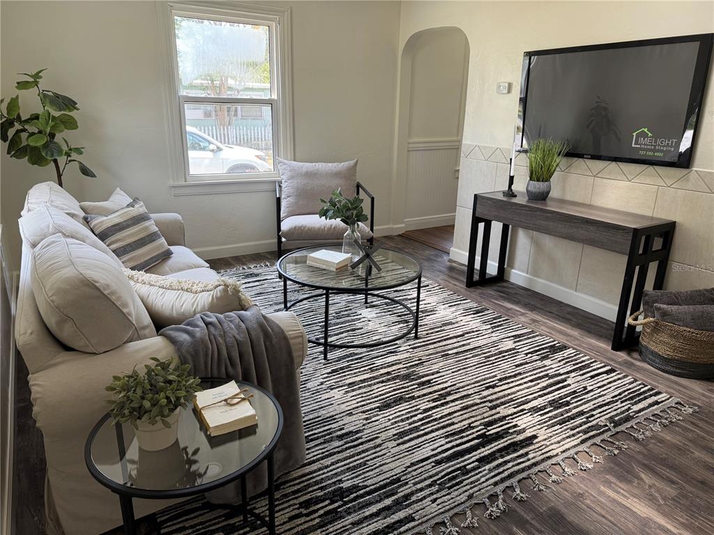 A living room features a sofa, accent chair, glass coffee table, and a wall-mounted television — 1419 55TH STREET S, GULFPORT, FL