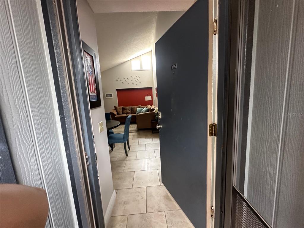 A view through an open front door into a tiled living area with vaulted ceilings — 3766 SOUTHPOINTE DRIVE UNIT U5, ORLANDO, FL