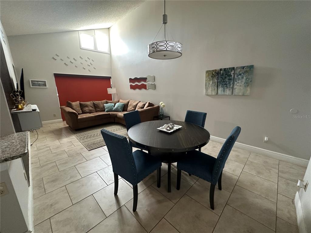 A dining area with a round table and blue chairs opens into a living room — 3766 SOUTHPOINTE DRIVE UNIT U5, ORLANDO, FL