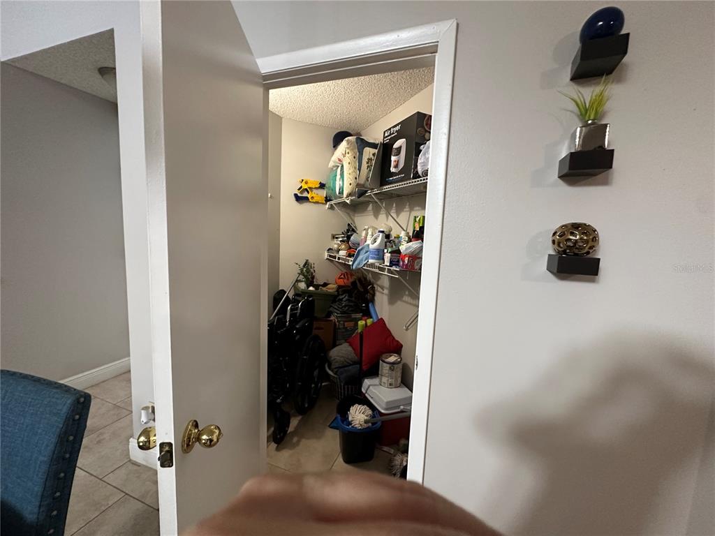 A view through an open door into a storage closet containing shelves and a wheelchair — 3766 SOUTHPOINTE DRIVE UNIT U5, ORLANDO, FL