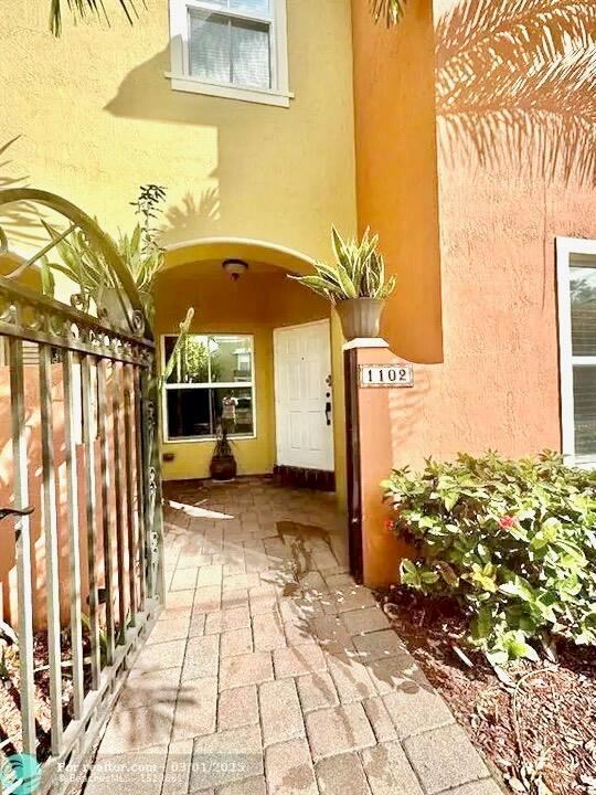 A paved walkway leads to the front entrance of a stucco home with a gate — 2851 W Prospect Road # 1102, Tamarac FL 33309, TAMARAC, FL