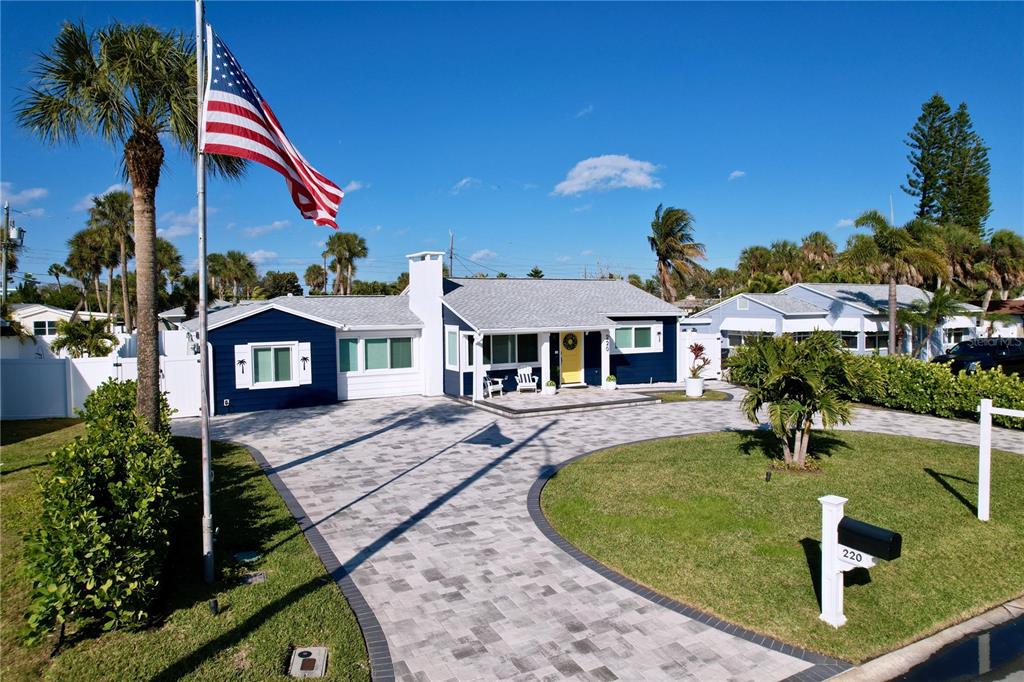 A blue house with a paved driveway, a yellow front door, and an American flag — 220 40TH AVENUE, ST PETE BEACH, FL