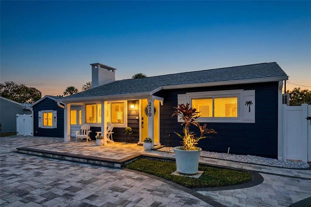 A blue house with a paved driveway, a front porch, and a small garden area — 220 40TH AVENUE, ST PETE BEACH, FL