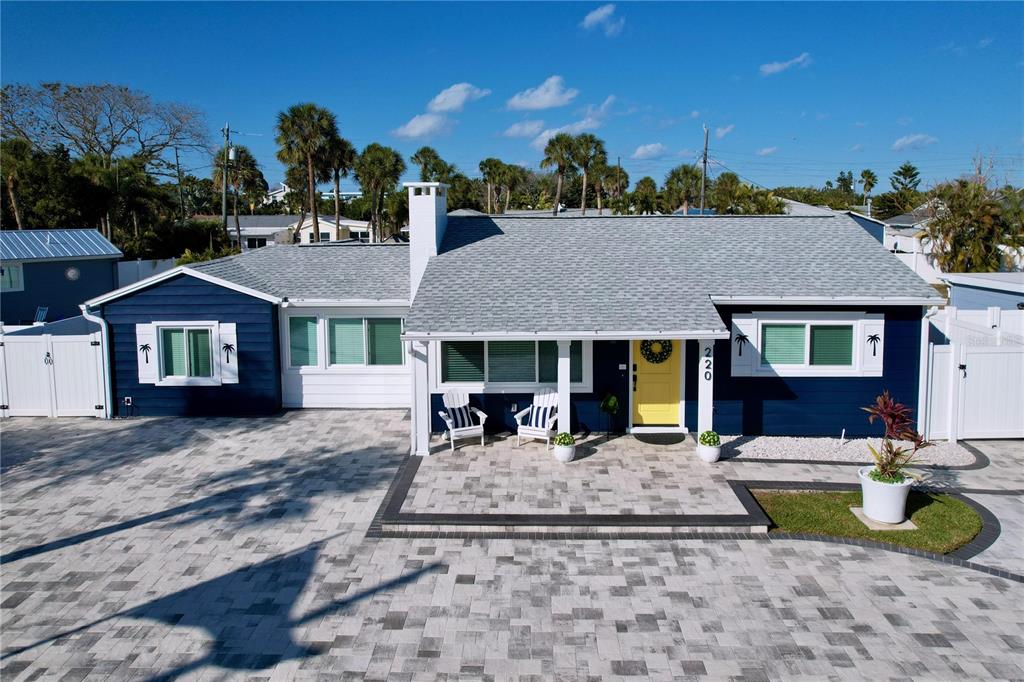 A blue house with a yellow front door and a large paver driveway — 220 40TH AVENUE, ST PETE BEACH, FL