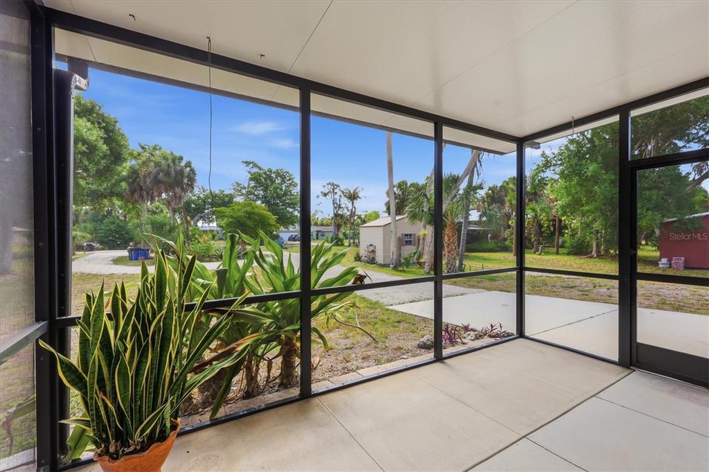A screened-in porch with a concrete floor overlooks a yard with trees and a shed — 788 HARMONY LANE, ENGLEWOOD, FL