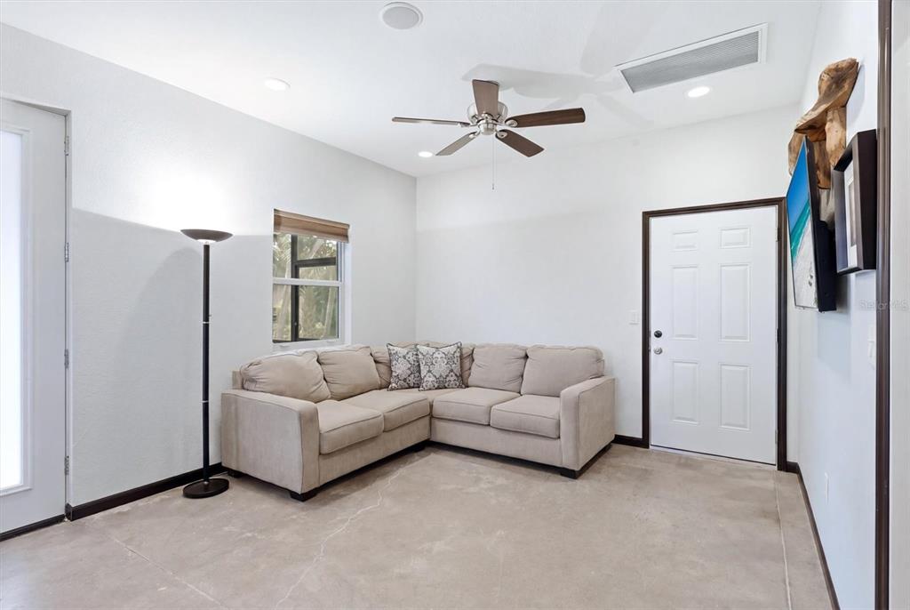 A living room features a beige sectional sofa, a floor lamp, and a ceiling fan — 788 HARMONY LANE, ENGLEWOOD, FL