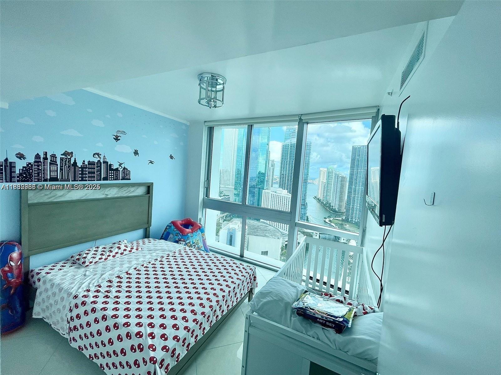 A bedroom features a Spider-Man themed bed, a white crib, and floor-to-ceiling windows overlooking city buildings — 350 S Miami Ave # 3602, Miami FL 33130, MIAMI, FL