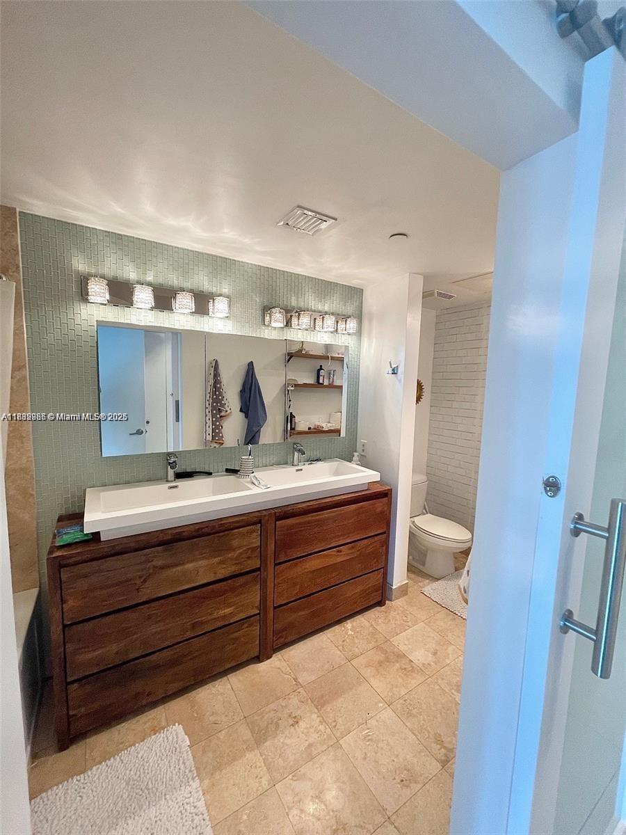 A bathroom features a double vanity with a wooden cabinet and a green tiled wall — 350 S Miami Ave # 3602, Miami FL 33130, MIAMI, FL