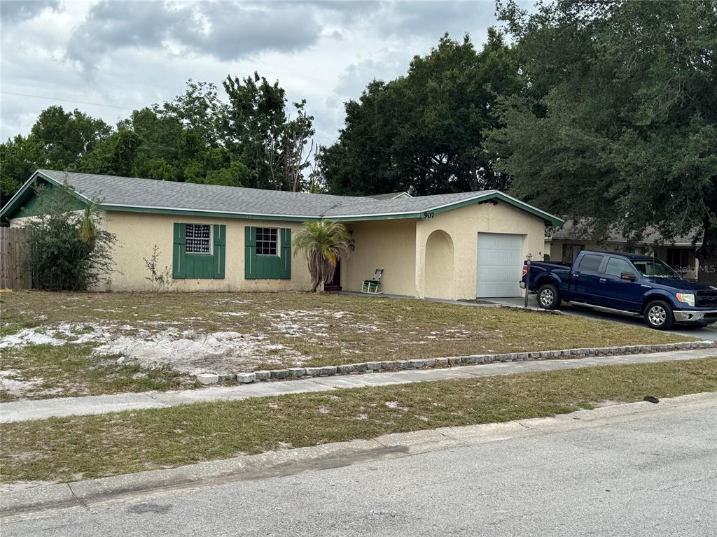 A single-story house with a beige stucco exterior, green shutters, and an attached garage — 907 HYLAND SPRINGS DRIVE, OCOEE, FL