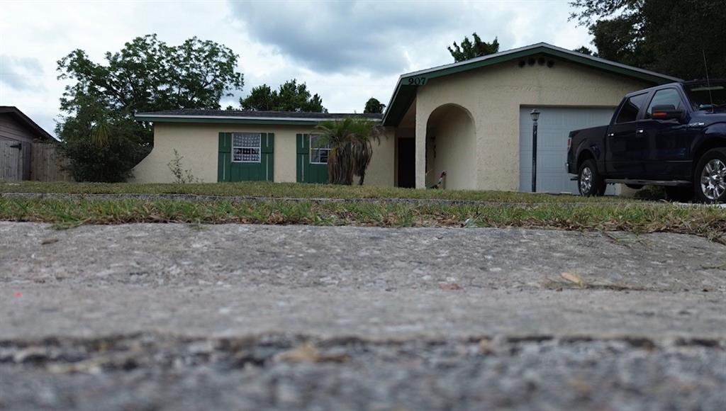 A low-angle view of a single-story house with green shutters and a dark pickup truck — 907 HYLAND SPRINGS DRIVE, OCOEE, FL