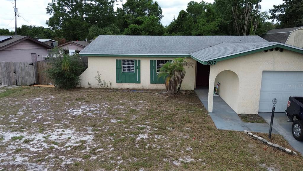 A single-story house with a light-colored stucco exterior, green shutters, and an attached garage — 907 HYLAND SPRINGS DRIVE, OCOEE, FL