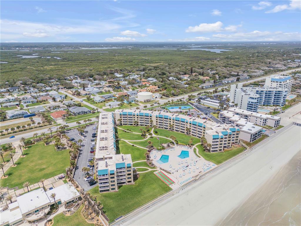 An aerial view shows a beachfront condominium complex with a pool, tennis courts, and parking — 4501 S ATLANTIC AVENUE UNIT 1150, NEW SMYRNA BEACH, FL