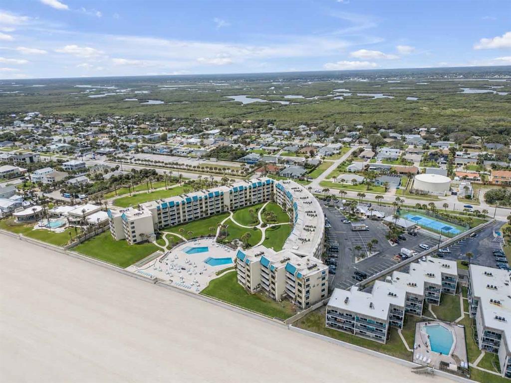 An aerial view shows a curved beachfront condominium complex with a pool and parking lot — 4501 S ATLANTIC AVENUE UNIT 1150, NEW SMYRNA BEACH, FL