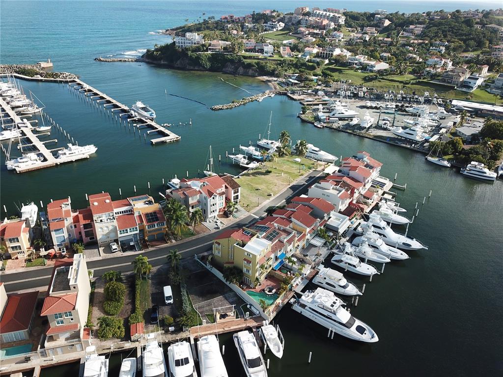 An aerial view shows a coastal marina with docked yachts and multi-story residential buildings — SAN MIGUEL 48, HUMACAO, PR
