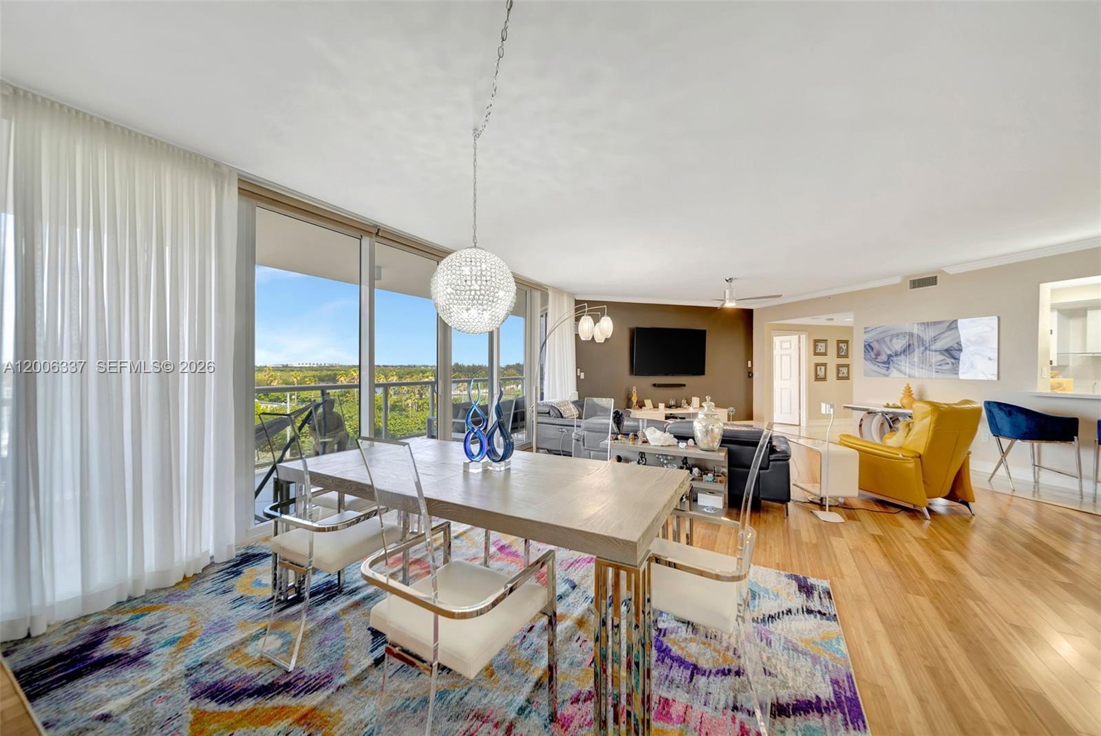 A dining area with a glass chandelier and modern furniture sits before floor-to-ceiling windows — 6051 N Ocean Dr # 603, Hollywood FL 33019, HOLLYWOOD, FL