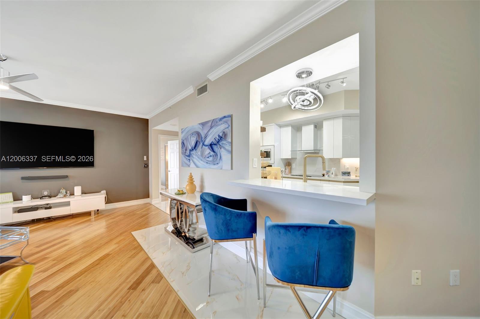 A living room with hardwood floors features a breakfast bar with blue velvet stools — 6051 N Ocean Dr # 603, Hollywood FL 33019, HOLLYWOOD, FL