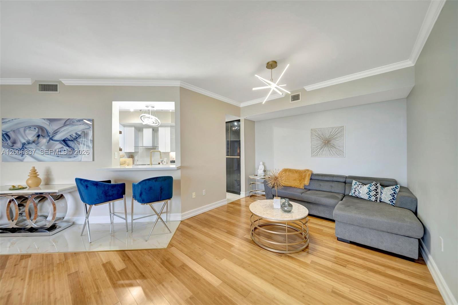 A living room features a grey sectional sofa, a marble coffee table, and blue barstools — 6051 N Ocean Dr # 603, Hollywood FL 33019, HOLLYWOOD, FL