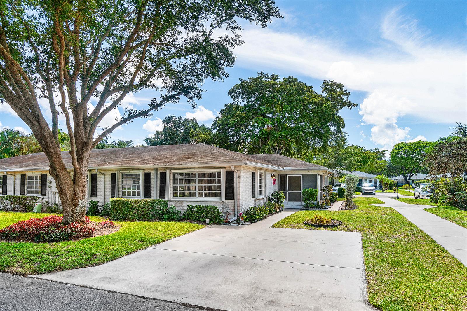 A single-story white brick house features a large tree, a concrete driveway, and landscaping — 10141 S 41st Dr Drive # 193, Boynton Beach FL 33436, BOYNTON BEACH, FL