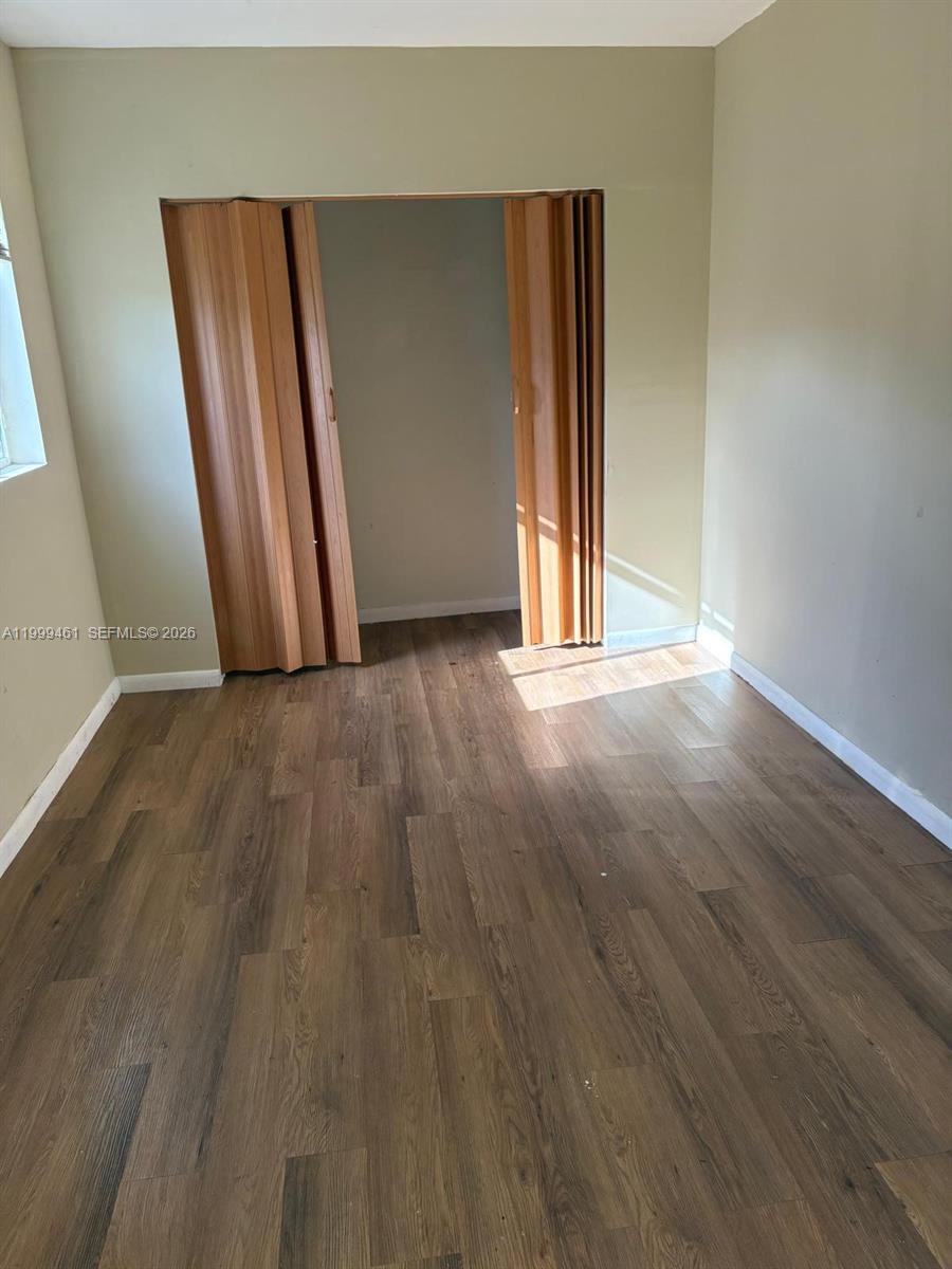 A bedroom features wood-look flooring, light-colored walls, and a wooden folding closet door — 1384 NW 27th St # 1382, Miami FL 33142, MIAMI, FL