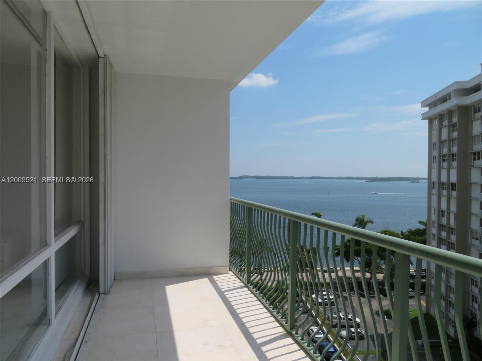A balcony with a green metal railing overlooks a body of water and a building — 1408 Brickell Bay Dr # 1002, Miami FL 33131, MIAMI, FL