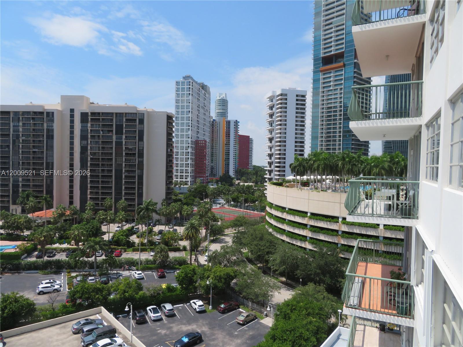 An elevated view shows a parking lot, palm trees, and several high-rise buildings — 1408 Brickell Bay Dr # 1002, Miami FL 33131, MIAMI, FL