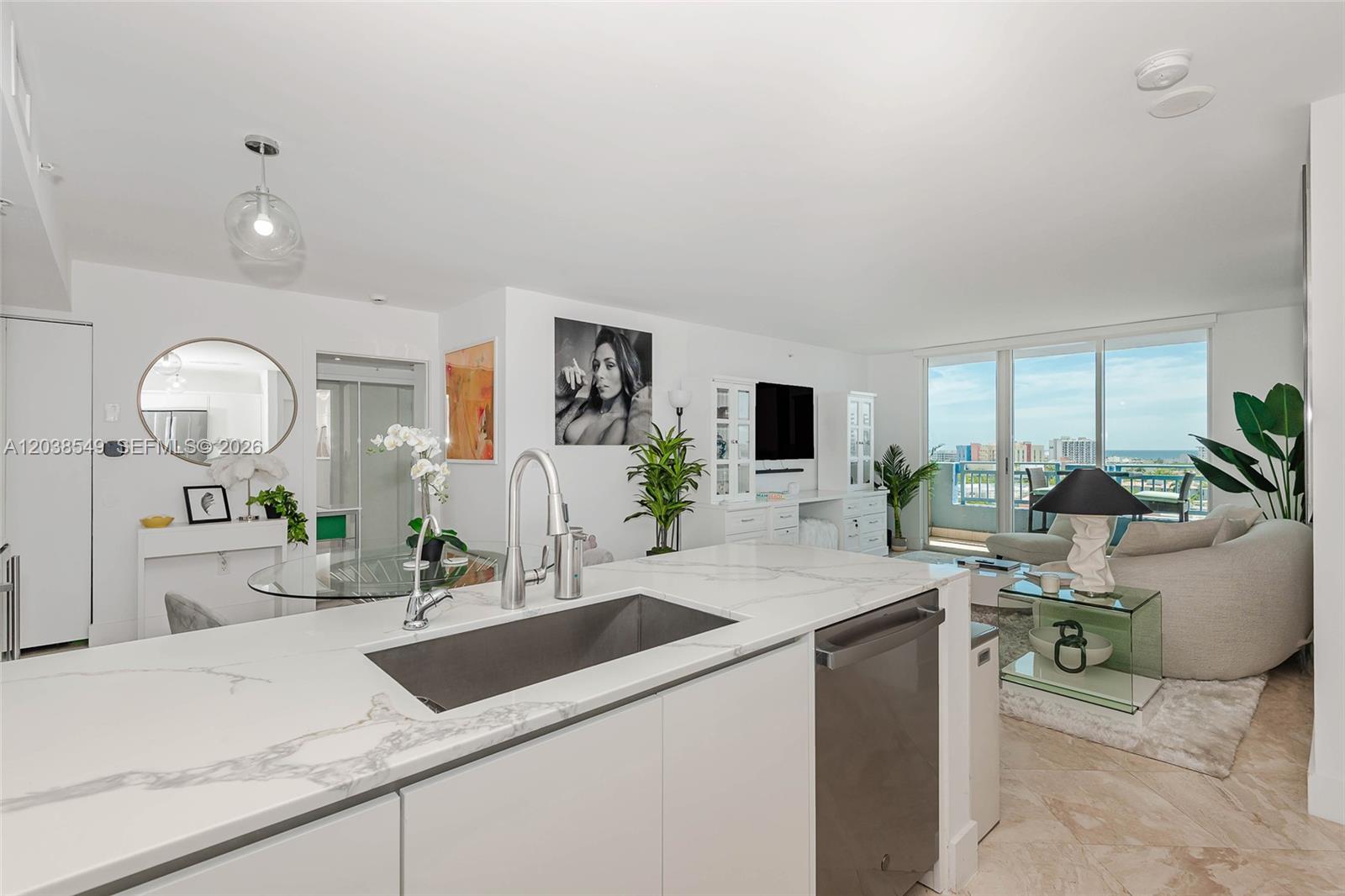 A modern kitchen island with a marble countertop overlooks a living area with balcony views — 90 Alton Rd # 1109, Miami Beach FL 33139, MIAMI BEACH, FL